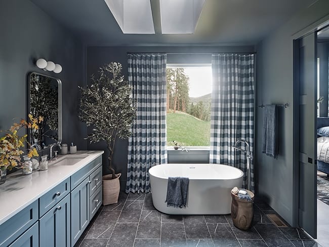 A soaking tub under two skylights in a dark gray bathroom