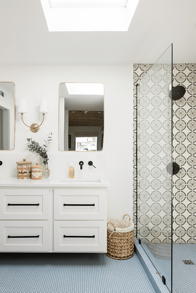 Bathroom with one skylight white walls and cabinet with geometric shower tile