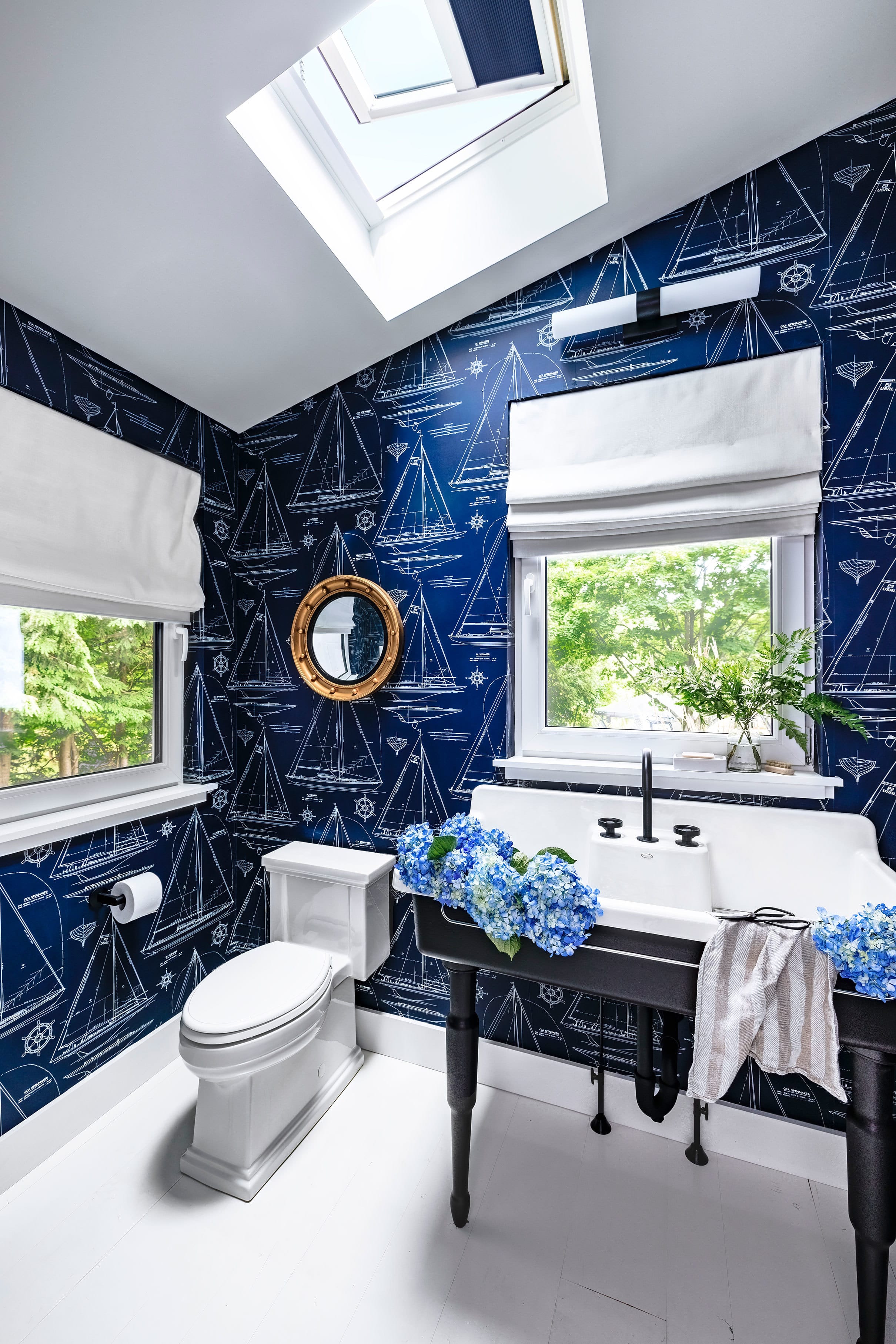 A laundry room with sunset colored pink and blue wallpaper highlighted by two skylights