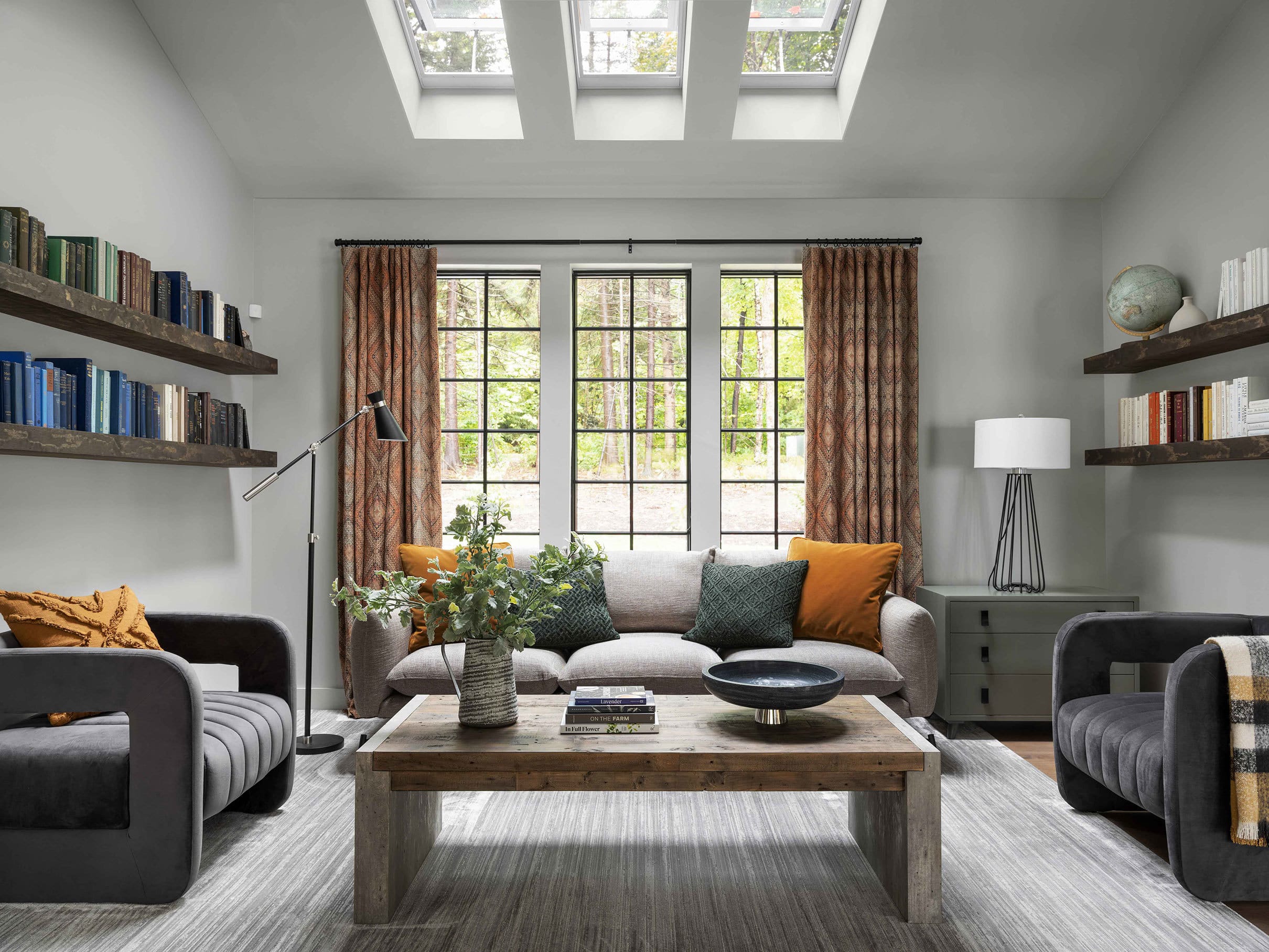 living room with three skylights, floating shelves, gray sofas and rust draperies